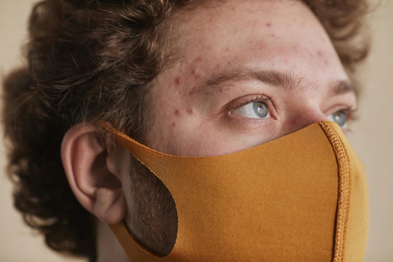 a close up of a person wearing a face mask, by Adam Marczyński, pimples, young adult male, cardboard, wearing honey