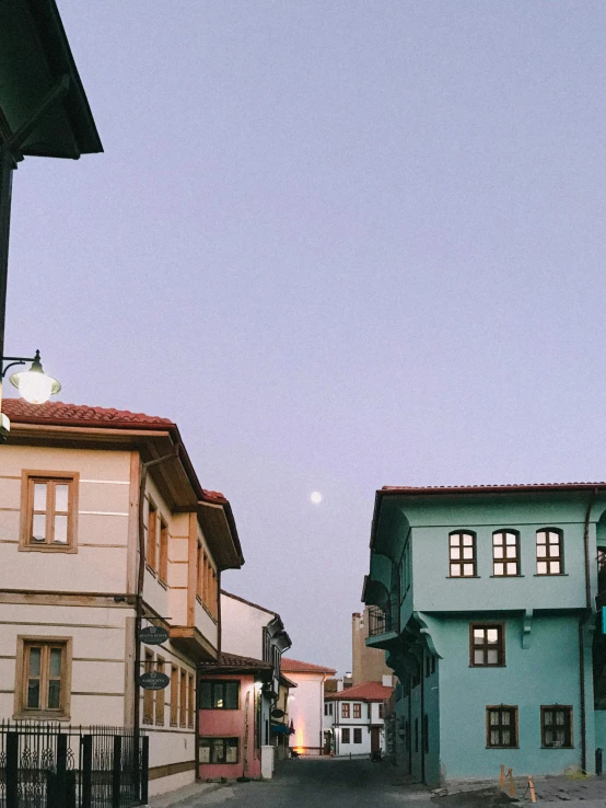 a couple of buildings sitting on the side of a road, by Tamas Galambos, pexels contest winner, art nouveau, ☁🌪🌙👩🏾, cyprus, trending on vsco, the moon is in the sky