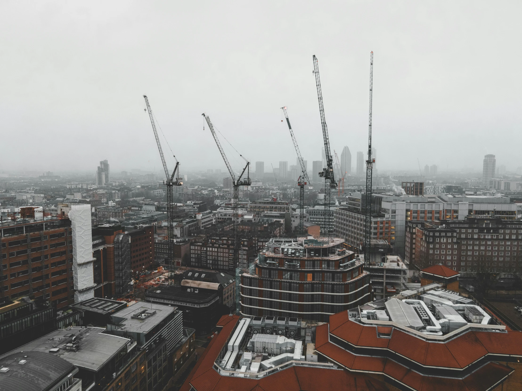 a view of a city from the top of a building, pexels contest winner, constructivism, grey, cranes, 80s london city, overcast gray skies