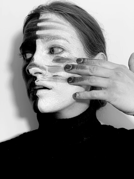 a black and white photo of a woman with white paint on her face, a black and white photo, inspired by Anna Füssli, hands shielding face, image split in half, makeup, ilustration