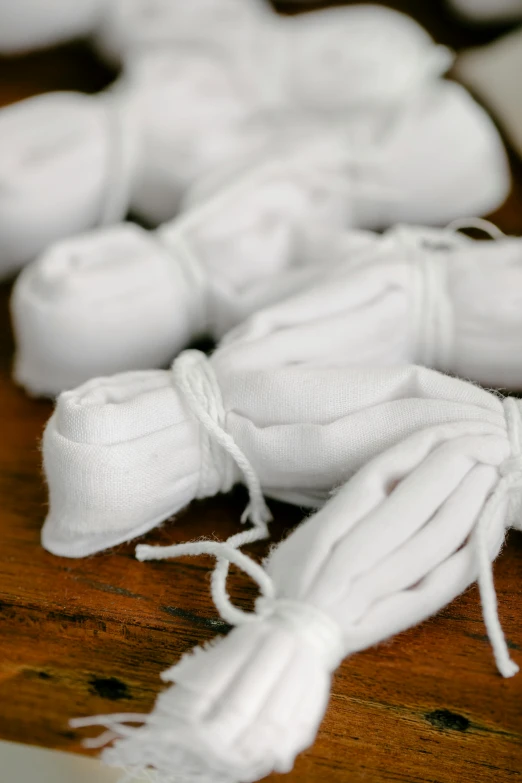 a bunch of white yarn sitting on top of a wooden table, covered in bandages, white shirts, cryogenic pods, dark. no text