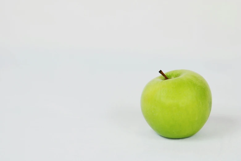 a green apple sitting on top of a white surface, a picture, unsplash, background image, low quality footage, 15081959 21121991 01012000 4k