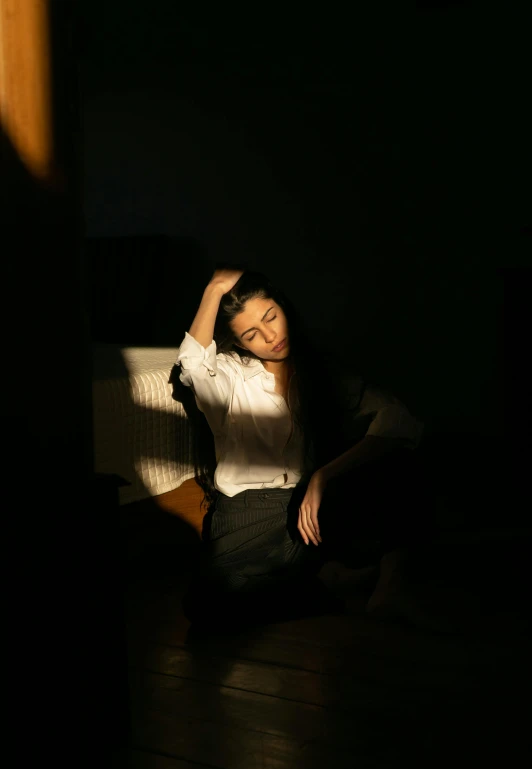 a woman sitting on the floor in the dark, inspired by Elsa Bleda, pexels, minimalism, soft sun lights, portrait of depressed teen, siting in a chair, play of light