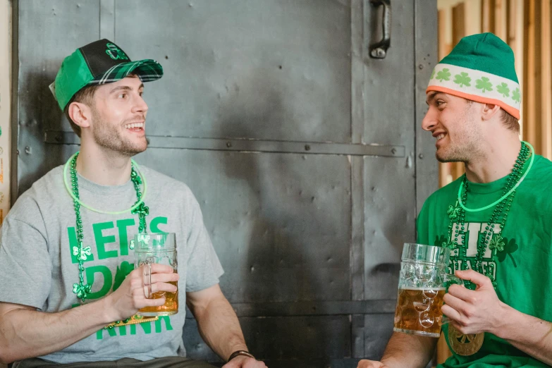 a couple of men sitting next to each other holding beers, pexels contest winner, green clothing, irish, green and white, standing still