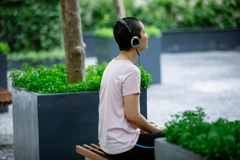 a person sitting on a bench with headphones on, inspired by Zheng Xie, unsplash, happening, parks and gardens, wearing black headphones, head turned, circular