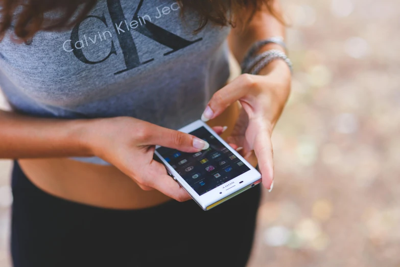 a close up of a person holding a cell phone, by Julia Pishtar, trending on pexels, wearing a crop top, calvin klein photography, 15081959 21121991 01012000 4k, avatar image