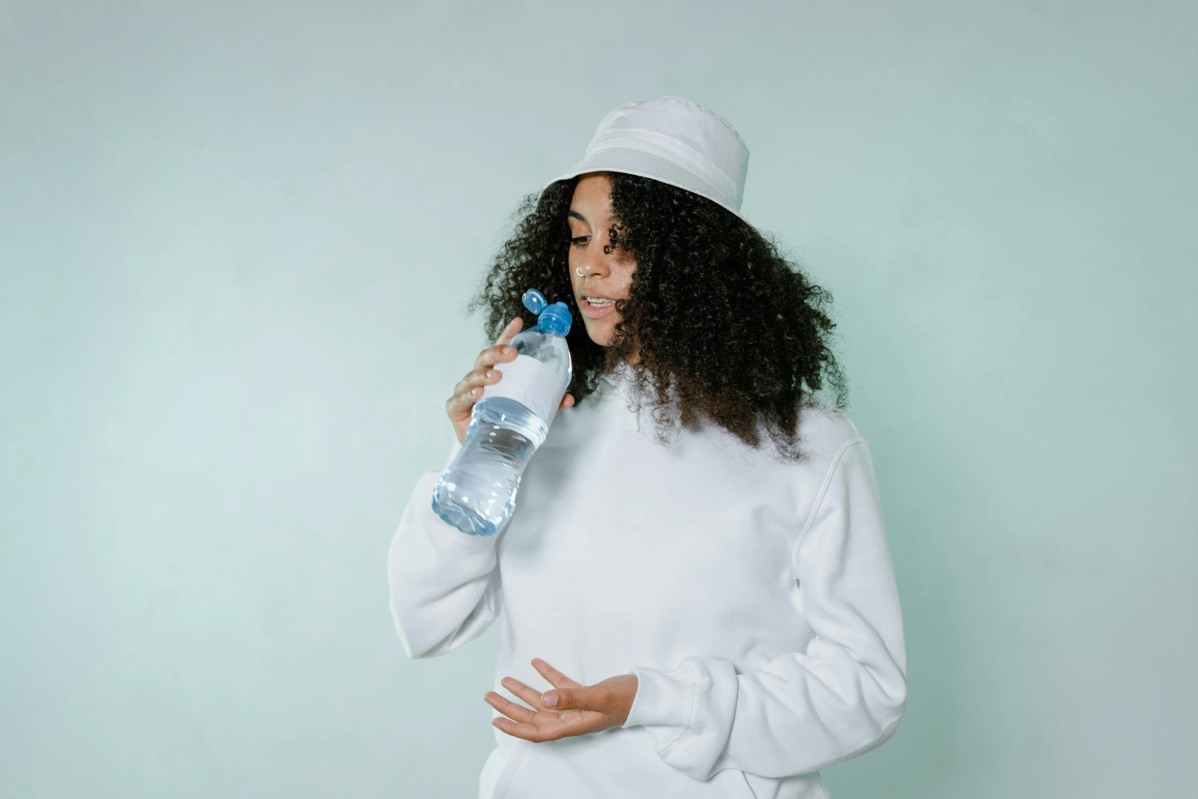 a woman talking on a cell phone while holding a bottle of water, with rap cap on head, white and pale blue, high quality product image”, curls