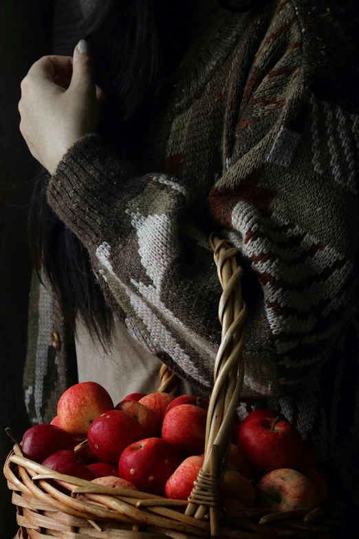 a woman holding a basket full of apples, a still life, inspired by Anna Füssli, shutterstock contest winner, dark and muted colors, cardigan, peru, detail