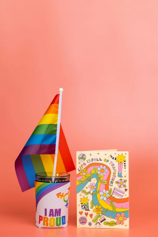 a cup of coffee with a rainbow flag next to it, by Winona Nelson, folk art, cereal box, art toys on a pedestal, dwell, promo image