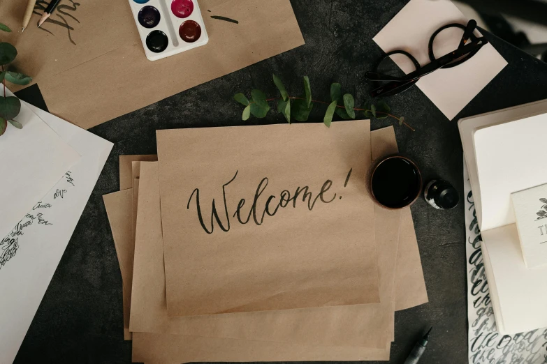 a bunch of papers sitting on top of a table, by Emma Andijewska, trending on pexels, welcome, estrange calligraphy, background image, brown