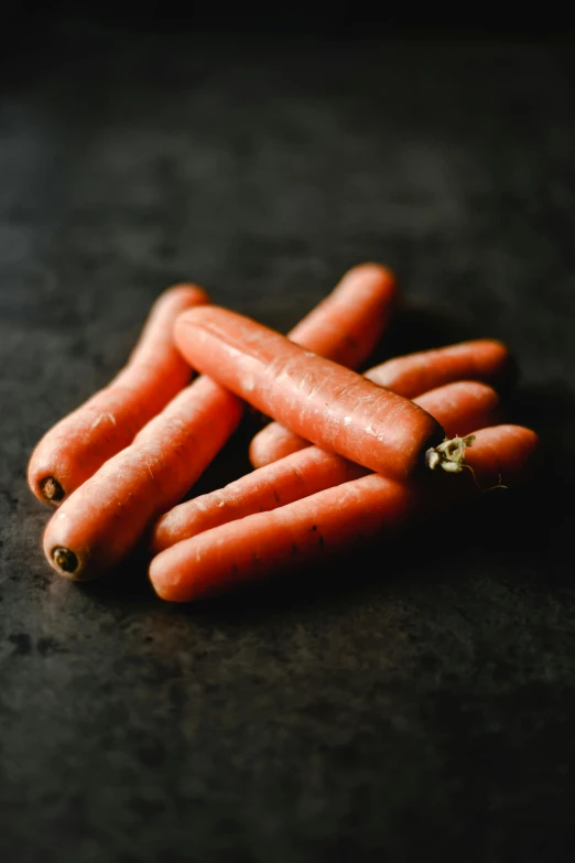 a bunch of carrots sitting on top of a table, in front of a black background, thumbnail, high quality product image”, slightly red