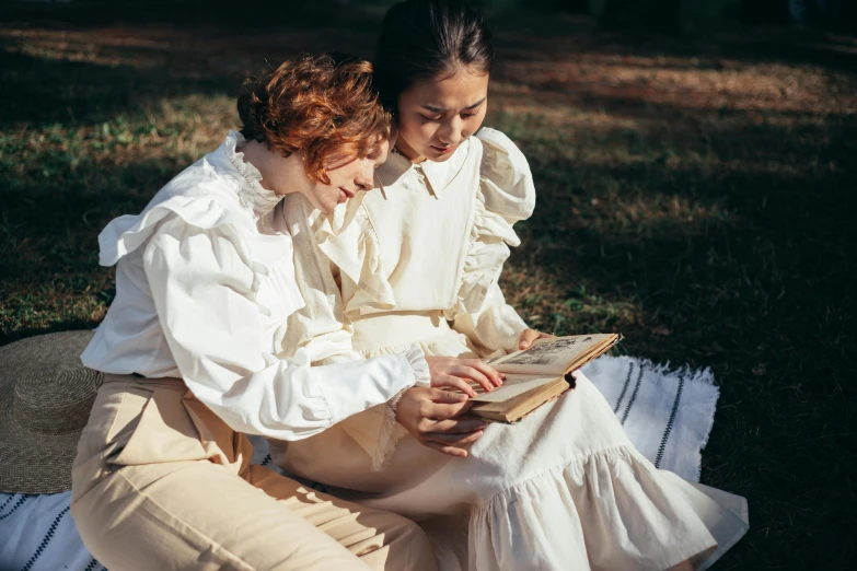 two women sitting on a blanket reading a book, inspired by William Stott, pexels contest winner, arts and crafts movement, wearing a white button up shirt, voluminous sleeves, costume design made with love, french provincial furniture