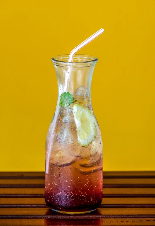 a pitcher filled with a drink sitting on top of a wooden table, lime and violet, trapped in tall iced tea glass, promo image, raspberry banana color