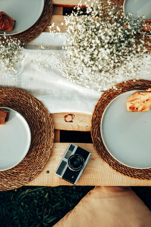 a table topped with plates of food next to a camera, minimalism, cottagecore hippie, couple, natural materials, snapchat photo