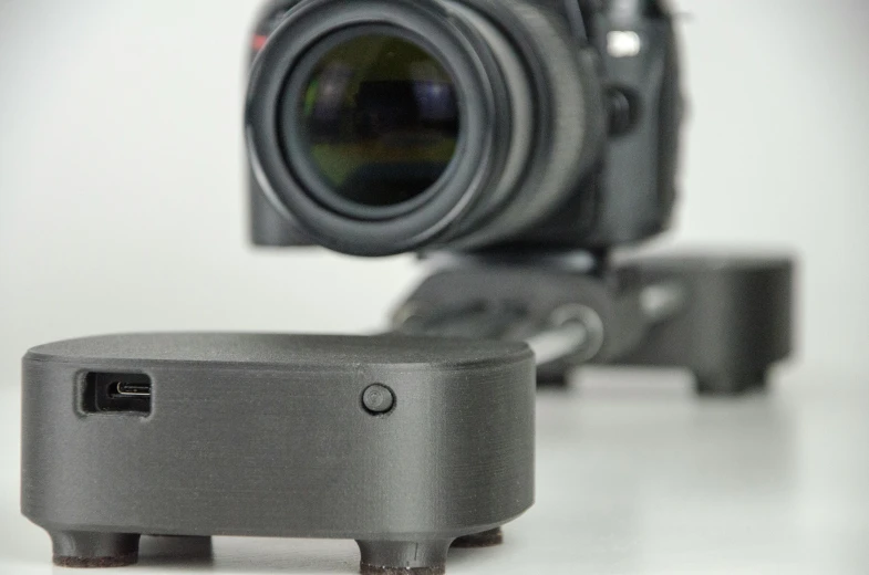 a small projector sitting on top of a table next to a camera, a picture, walking towards camera, timelapse, robotic platform, product photography