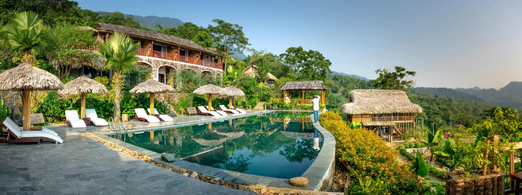 an outdoor swimming pool with lounge chairs and thatched umbrellas, pexels contest winner, happening, mountainous jungle setting, vietnam, front facing, ecovillage