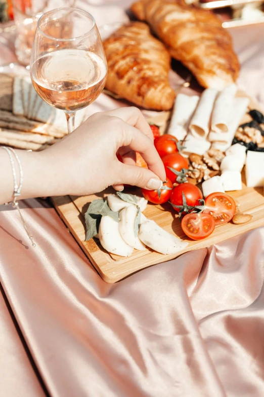 a person sitting at a table with a tray of food, a still life, by Julia Pishtar, trending on pexels, romanticism, eating a cheese platter, wearing a luxurious silk robe, summer day, background image