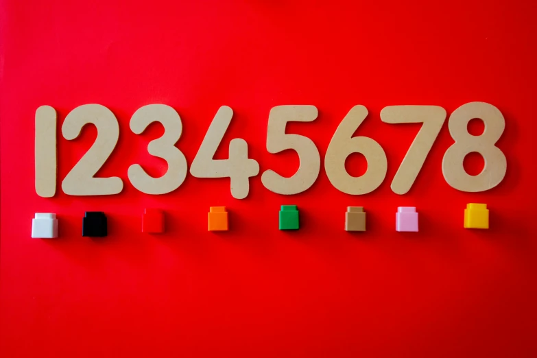 a close up of a number on a red wall, by Julia Pishtar, trending on unsplash, academic art, wooden art toys, various sizes, 2717433015, gold and red