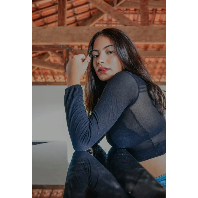 a woman sitting on top of a wooden bench, mesh shirt, wearing a dark shirt and jeans, colombian, instagram photo