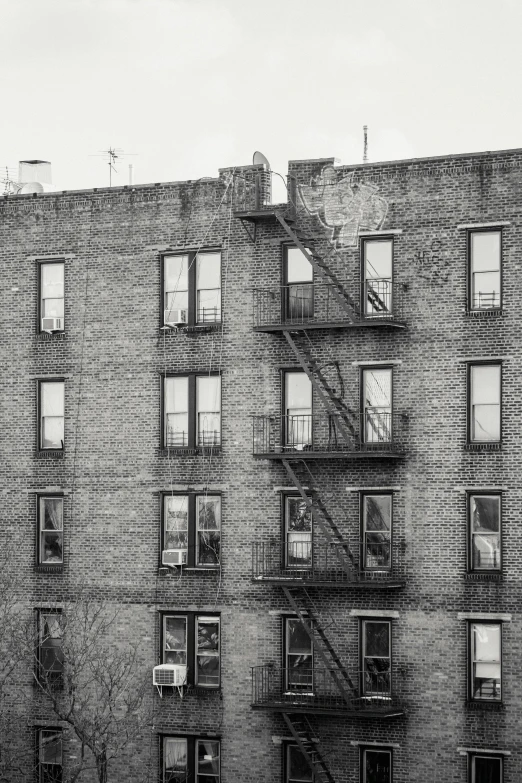 a black and white photo of an apartment building, a black and white photo, inspired by André Kertész, harlem renaissance, fine art print, long shot from back, a quaint, an abandoned