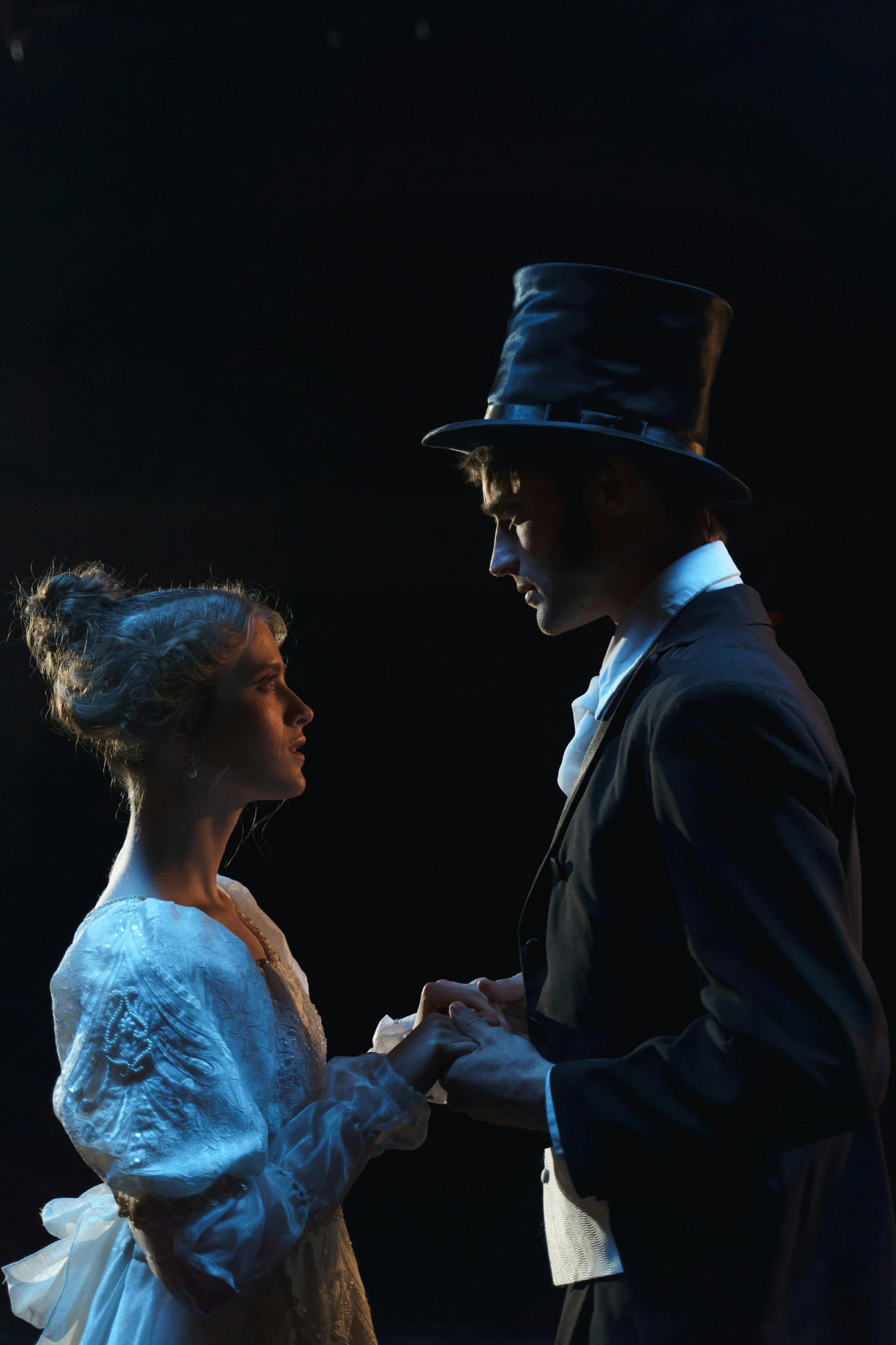 a man and a woman standing next to each other, a portrait, by Alice Mason, romanticism, theatrical lighting, wearing a top hat, facing each other, lachlan bailey