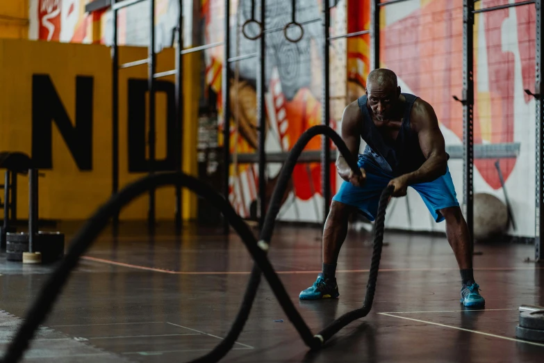 a man holding a battle ropes in a gym, a portrait, pexels contest winner, shaq, avatar image, background image