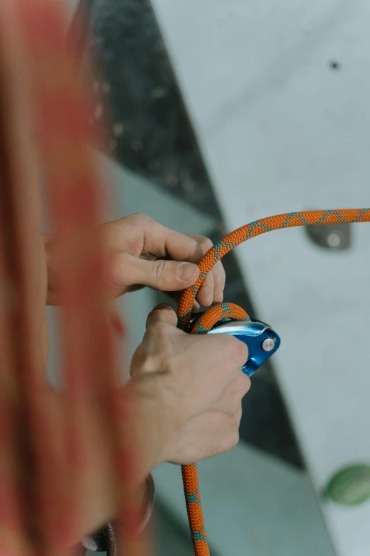 a woman tying a rope to a climbing wall, pexels contest winner, blue and orange, low quality footage, micro detail, top down