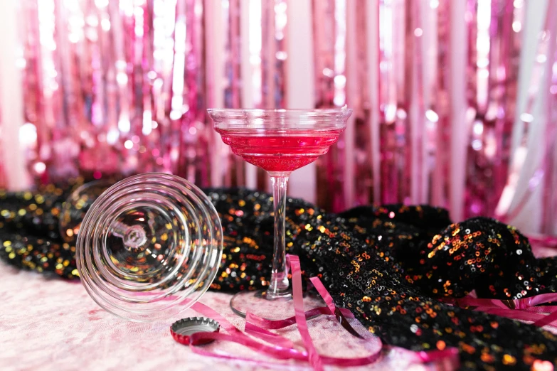 a pink cocktail sitting on top of a table, by Julia Pishtar, glitter background, 1 9 2 0 s cloth, background image, detail shot