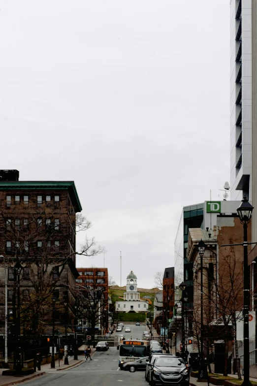 a street filled with lots of traffic next to tall buildings, neoclassical tower with dome, quebec, bleak, green square