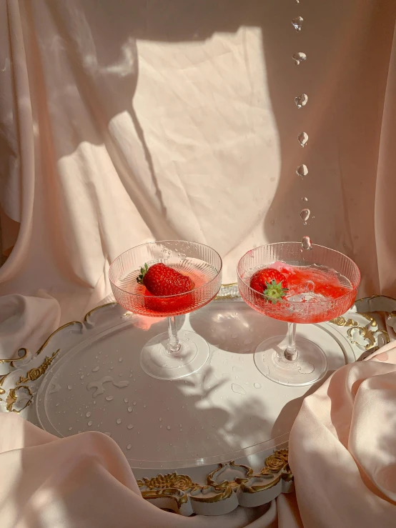 a couple of wine glasses sitting on top of a table, by Ndoc Martini, neo-romanticism, strawberries, 🎀 🧟 🍓 🧚, soft aesthetic, jelly - like texture. photograph