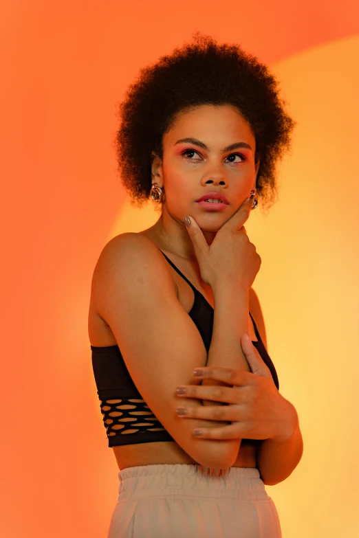 a woman posing for a picture in front of an orange background, wearing a black cropped tank top, mixed race woman, deep in thought, promotional image