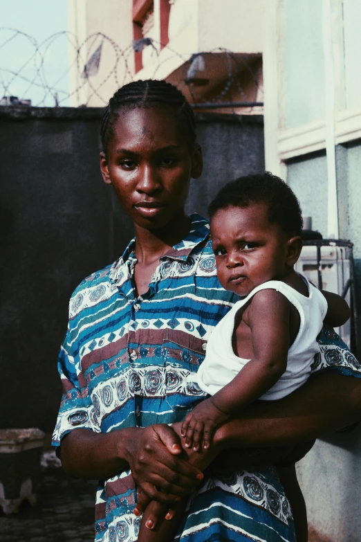 a woman holding a child in her arms, an album cover, pexels contest winner, man is with black skin, 35mm 1990, multicoloured, ( ( dark skin ) )