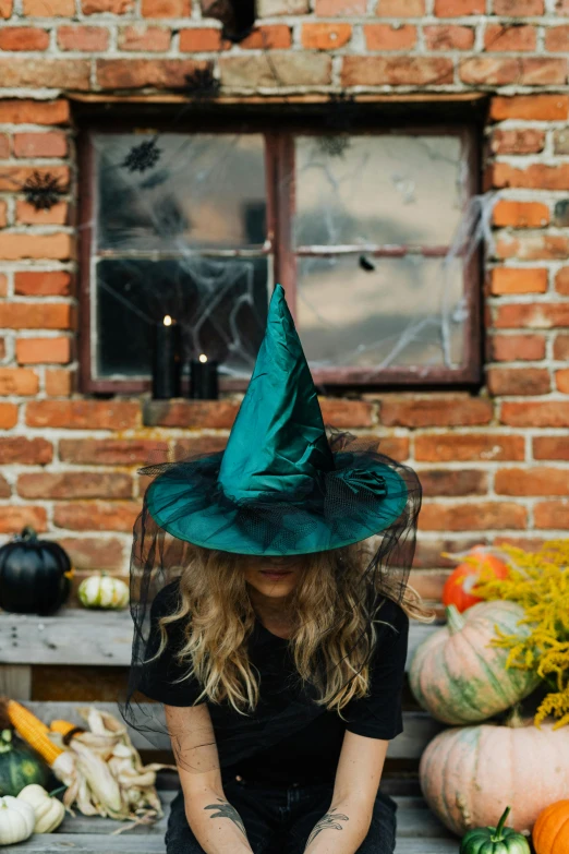 a woman in a witches hat sitting on a bench, pexels contest winner, teal aesthetic, beistle halloween decor, medium, square