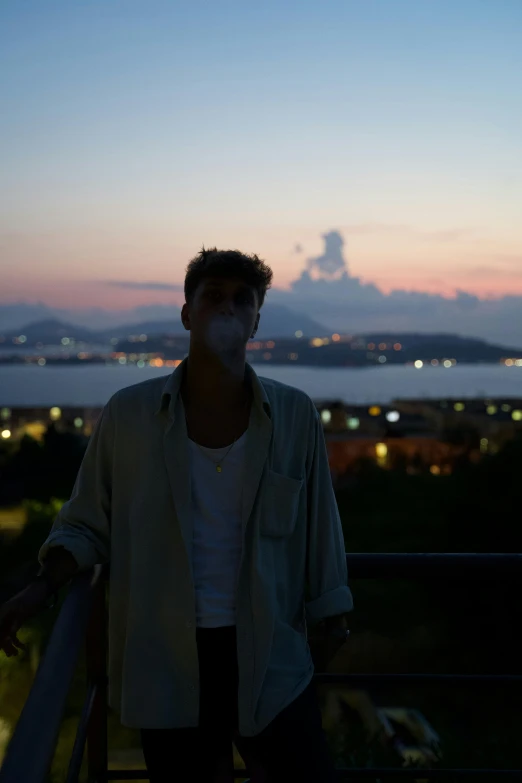 a man standing on a balcony with a cigarette in his mouth, an album cover, by Alexis Grimou, pexels contest winner, happening, ((sunset)), smoke - filled ， green hill, riccardo scamarcio, humid evening