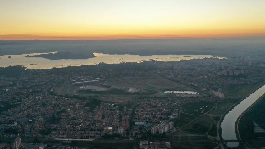 an aerial view of a city with a river running through it, by Alessandro Allori, pexels contest winner, hurufiyya, sunset panorama, ground haze, lake view, oscar niemeyer