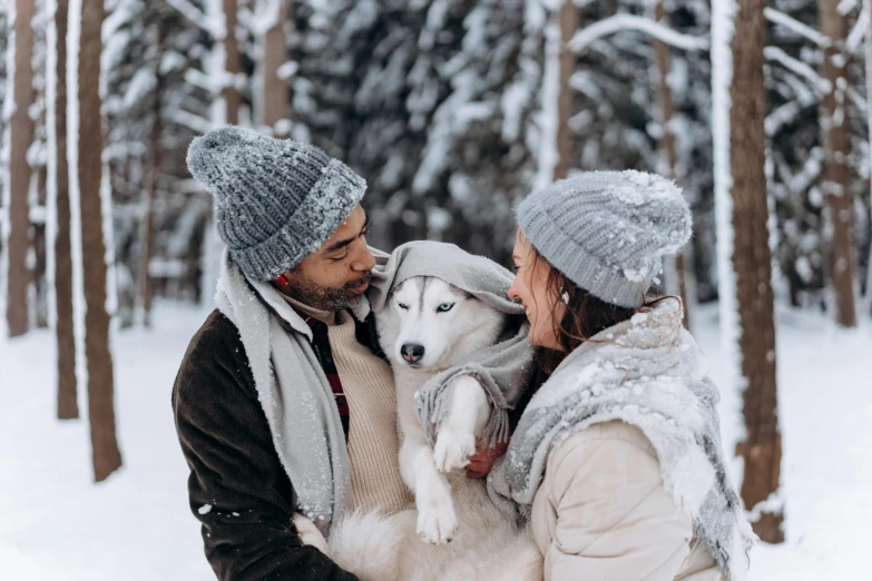 a man and woman holding a dog in the snow, by Julia Pishtar, pexels contest winner, he also wears a grey beanie, avatar image, white, elegantly dressed