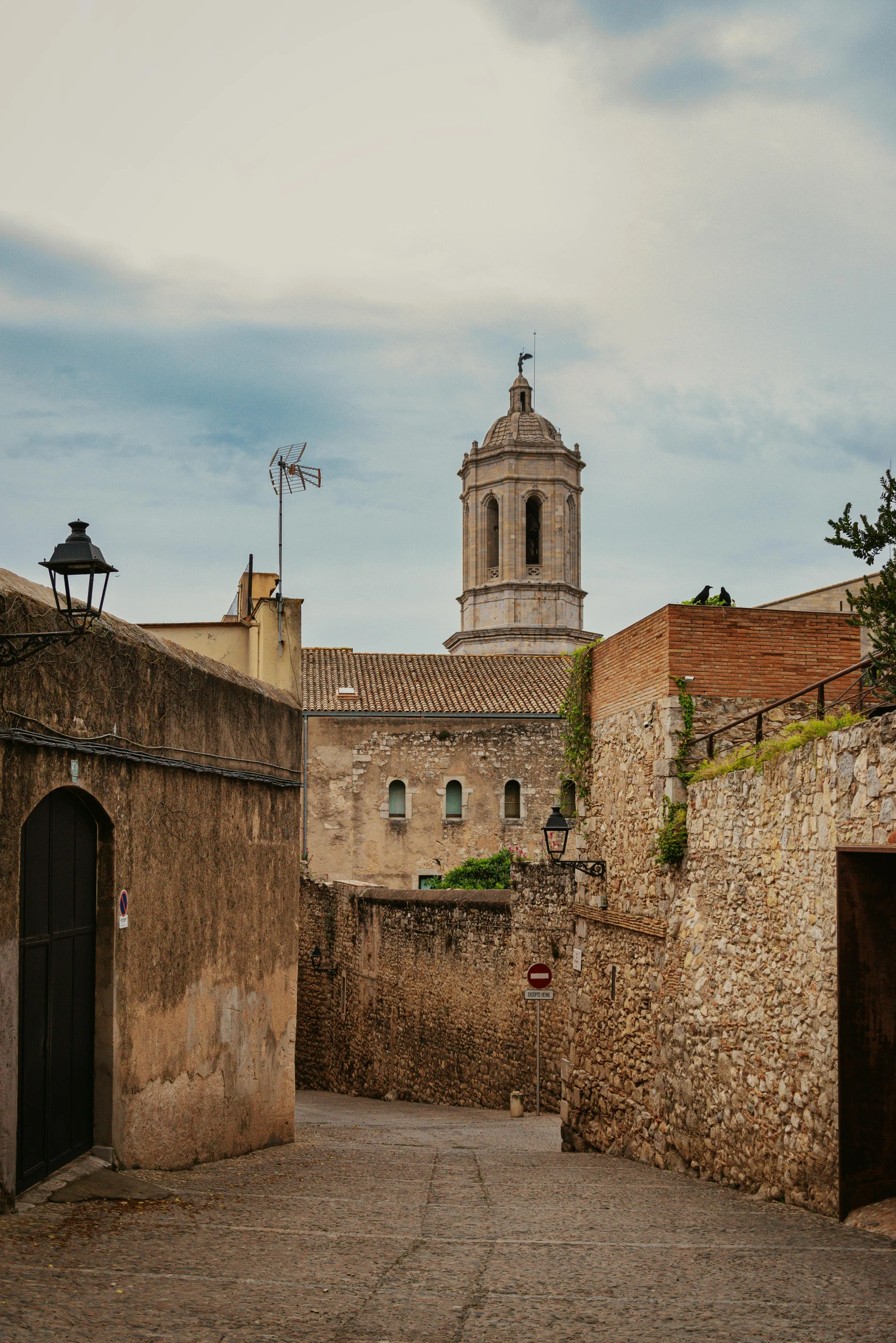 a cobblestone street with a clock tower in the background, by Carlo Carrà, pexels contest winner, romanesque, high walls, seen from far away, colour photograph, gothic quarter