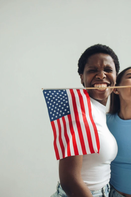 a couple of women standing next to each other holding american flags, a picture, shutterstock, licking tongue, diverse ages, programming, with a straw