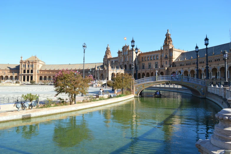 a bridge over a river in front of a building, spanish princess, square, central hub