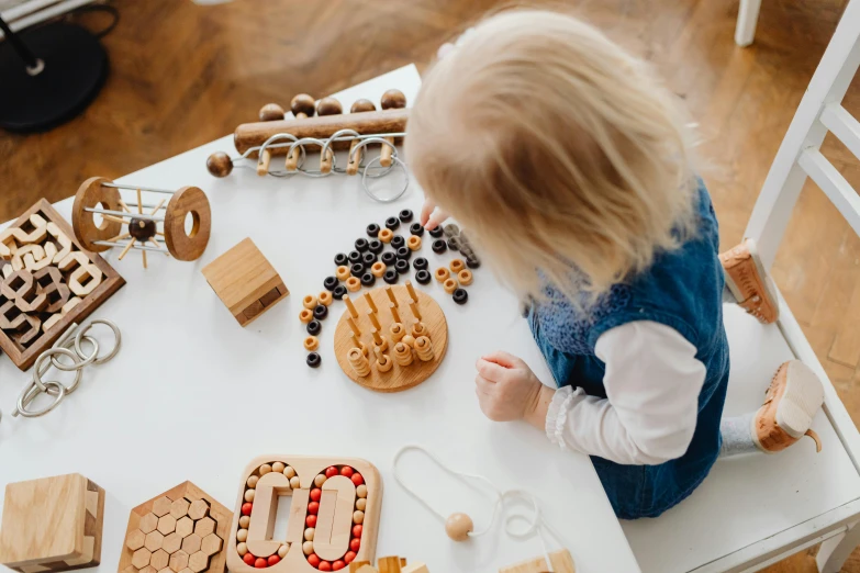 a little girl playing with wooden toys on a table, an album cover, by Emma Andijewska, pexels contest winner, tactile buttons and lights, maths, profile image, rounded shapes