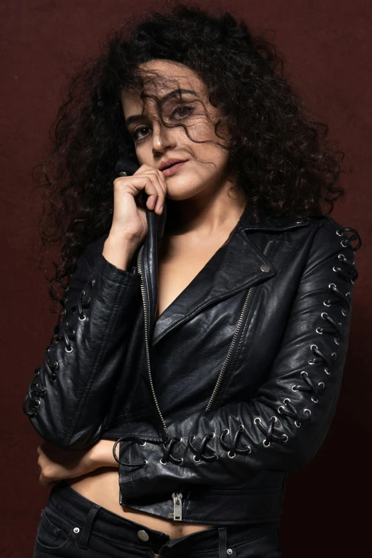 a woman in a leather jacket posing for a picture, an album cover, trending on pexels, renaissance, (dark shorter curly hair), curves, portait image, actress