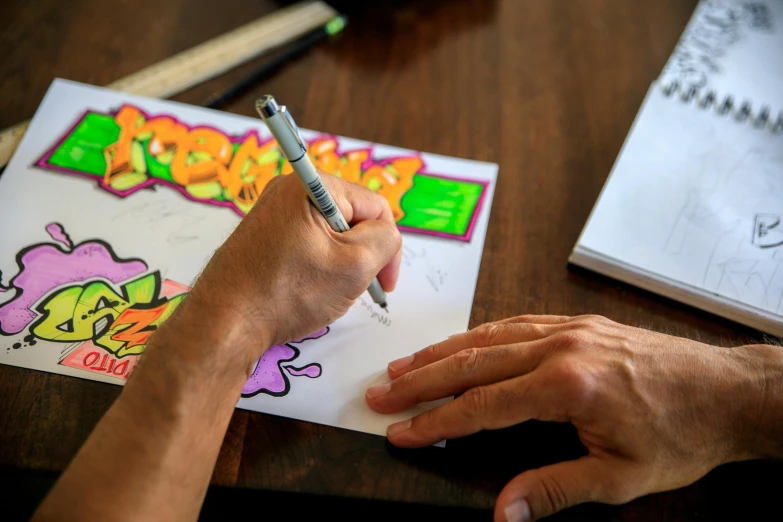 a person is drawing on a piece of paper, by Daarken, pexels contest winner, kenny scharf, fan favorite, coloring pages, hand on table