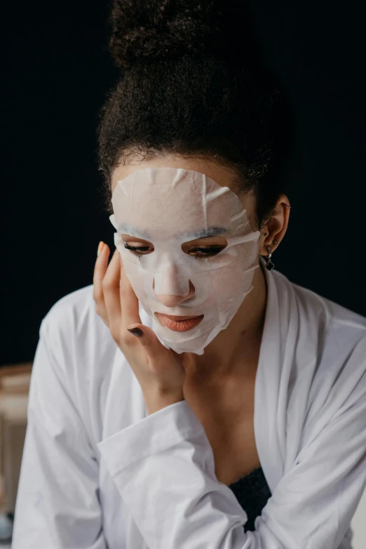 a woman sitting on a bed with a sheet on her face, trending on pexels, renaissance, geisha mask, made of lab tissue, glossy surface, facial scar