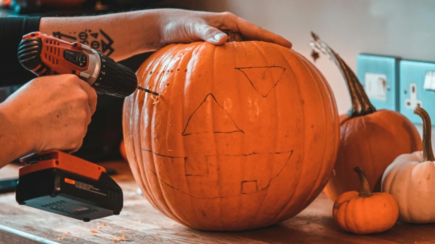 a person carving a pumpkin with a power drill, pexels contest winner, 🦩🪐🐞👩🏻🦳, promo image, stick and poke, 1 4 9 3