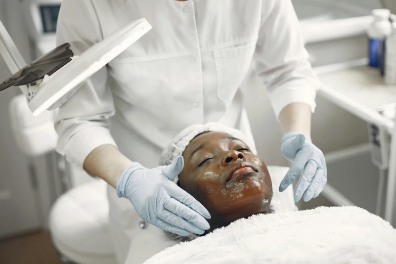 a woman getting a facial mask at a beauty salon, a photo, by Meredith Dillman, shutterstock, renaissance, with brown skin, medical photography, square facial structure, unedited