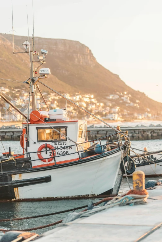 a couple of boats that are sitting in the water, by Daniel Seghers, pexels contest winner, fishing boat, docked at harbor, south african coast, warm light