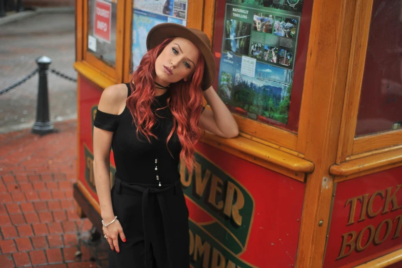 a woman leaning against the side of a bus, by Julia Pishtar, bella thorne, vibrant red hair, wearing black dress and hat, avatar image