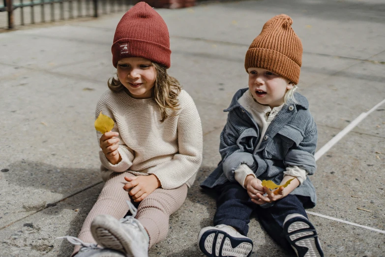 a couple of kids that are sitting on the ground, by Nina Hamnett, pexels contest winner, beanie hat, mini model, maroon, 🍁 cute