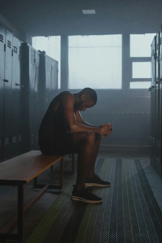 a man sitting on a bench in a locker, inspired by Terrell James, sweat drops, epk, jaylen brown, dark. no text