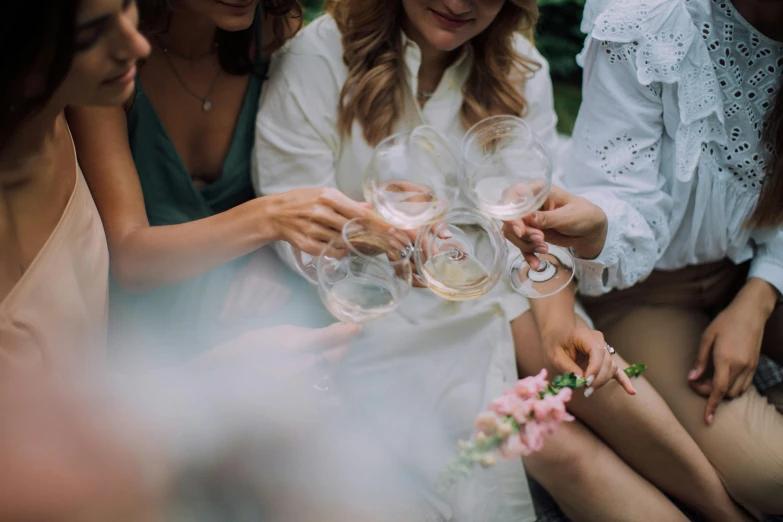 a group of women sitting next to each other holding wine glasses, pexels contest winner, happening, wearing white cloths, in a circle, close up shots, background image